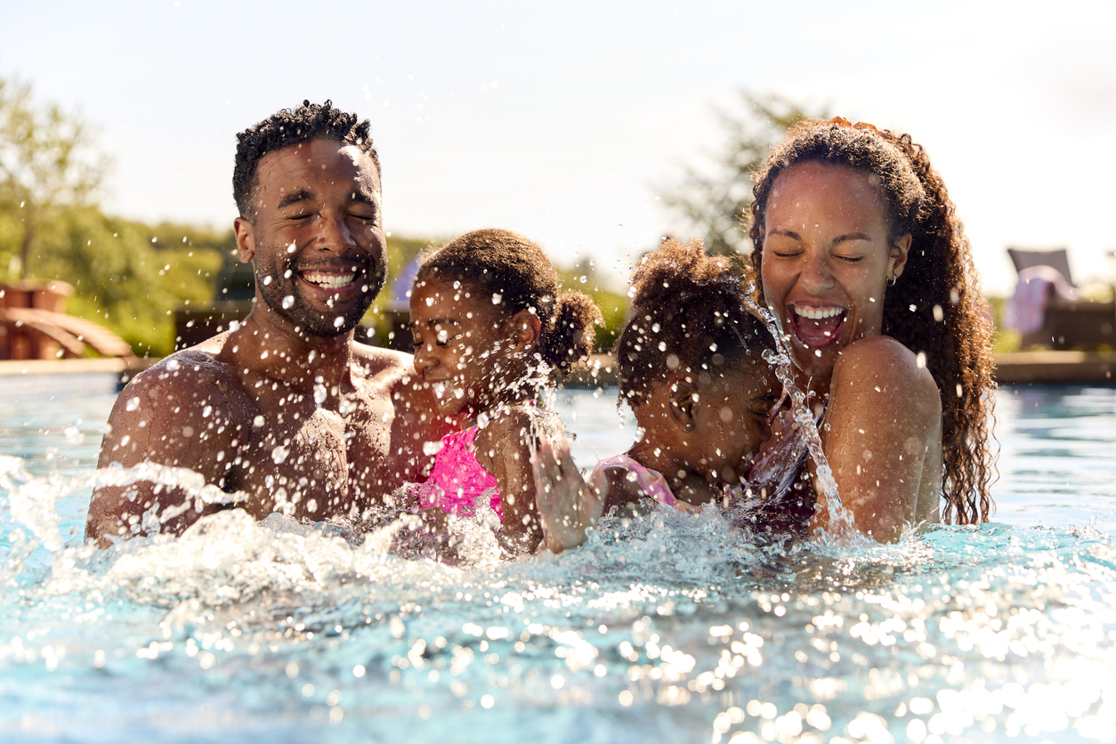 family playing in a pool at a cabin resort in the mountains.