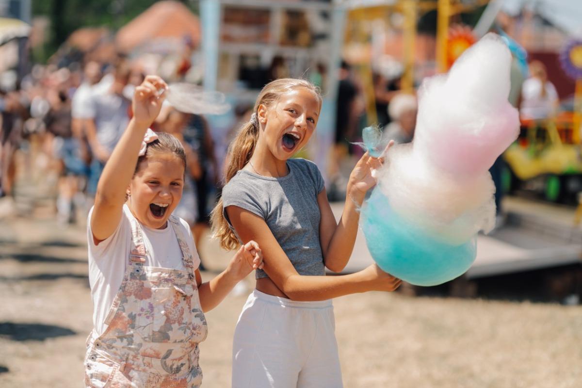 Two young girls at a local county fair with a cotton candy creation and they are loving it.