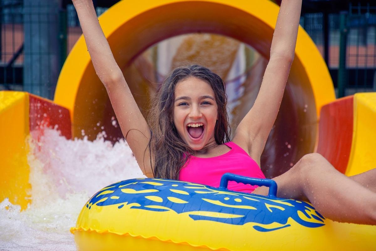cheerful girl with hands up on a waterpark ride in a tube.